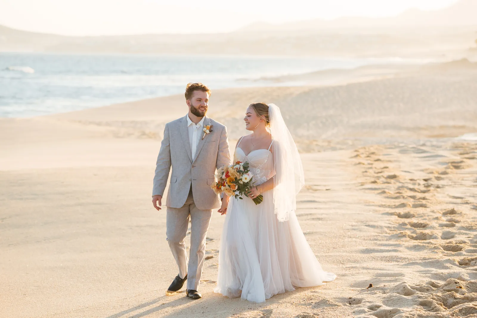 Couple walking on the beach in wedding attire